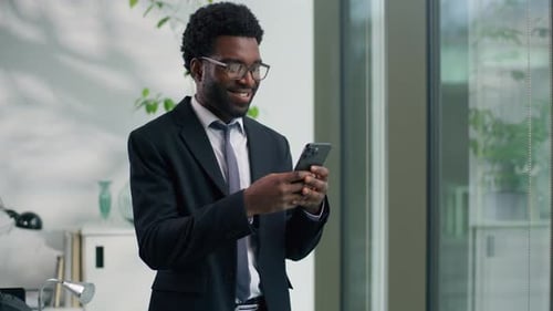 Smiling African American Businessman Using Smartphone in Office Business Man Ethnic Male Guy Looking