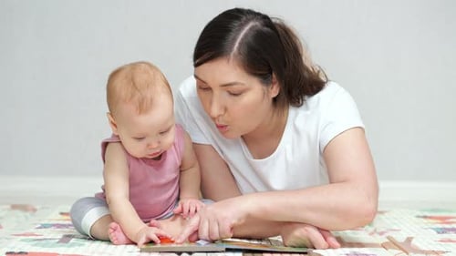 Mother Reads Book to Baby on Play Mat