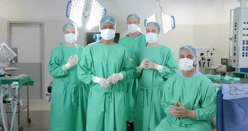 Portrait of diverse surgeons wearing surgical gowns in operating theatre, slow motion