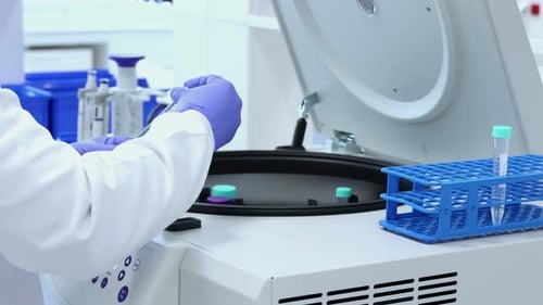 Technician Places Test Tubes in a Centrifuge Machine