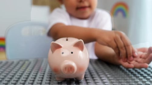 Nahaufnahme kleines Mädchen, das zu Hause Münzen ins Sparschwein steckt - Geld sparen und Zukunftskonzept