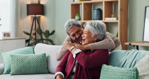 Loving Senior Couple Embrace on Couch at Home