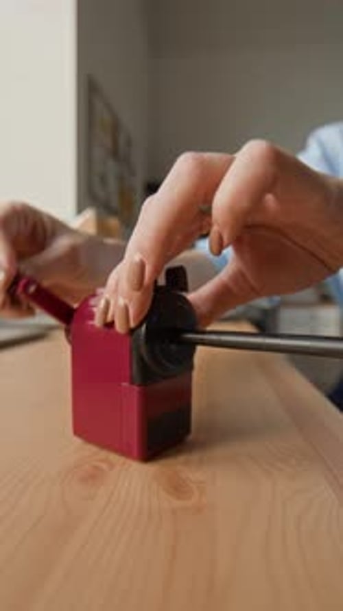 Employee Using Desktop Pencil Sharpener on Wooden Office Desk