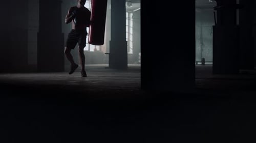 African american boxer kicks punchbag during intense boxing training workout in gym