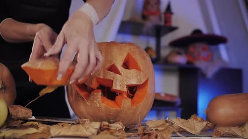 A Girl Covers a Carved Pumpkin for Halloween with a Piece Cut Out of the Pumpkin