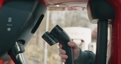 Man plugs the charging cable into the charging station