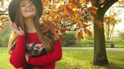 Woman Waving Hand In Autumn Park