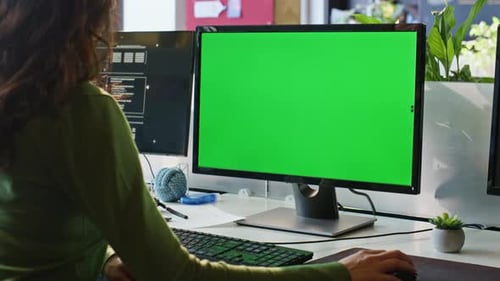 Woman working at desk using computer with greenscreen