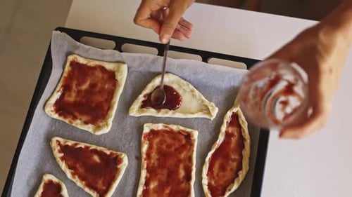 Le pâtissier étale de la confiture sur des pâtons