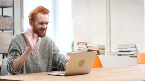Young Adult Waving During Video Call on Laptop