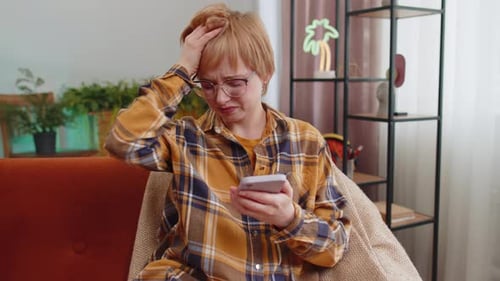 Woman Uses Smartphone with Confused Expression Indoors