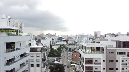 Drone view of city moving forward with modern residential buildings with traffic in the background.