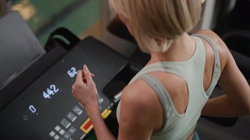 Woman Walking on Treadmill and Monitoring Heart Rate on Smartwatch in Gym