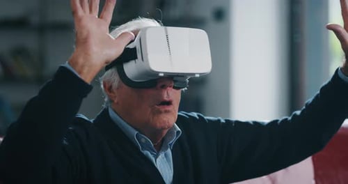 Close up of excited mature senior man is having fun using vr glasses in living room at home.