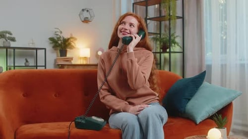 Woman chatting happily on retro telephone at home