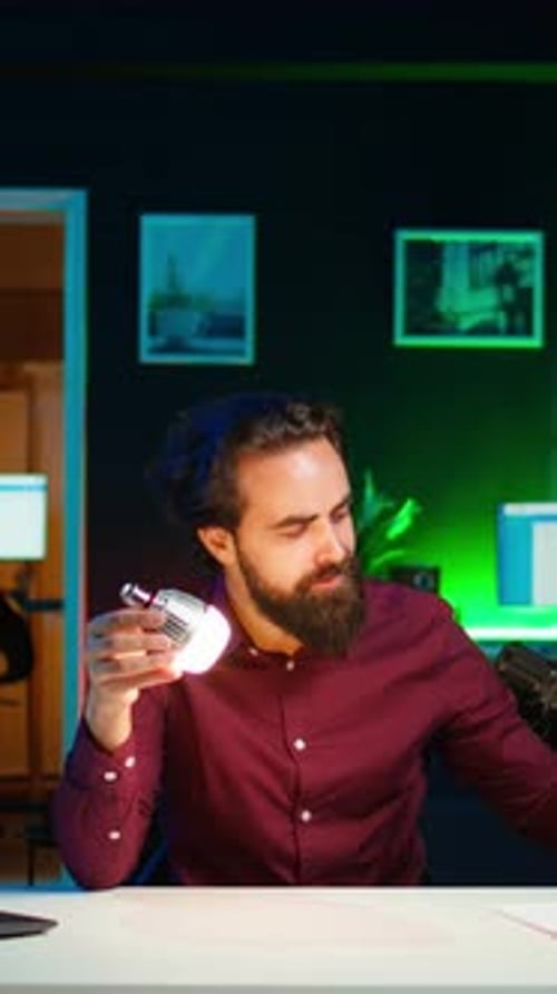 Vertical Video Tech Guru in Dimly Lit Apartment Studio Filming Smart Light Bulb Review