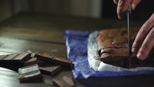 Chefkoch schneidet Schokoladendessert auf dem Tisch. Schokoladenkuchen schneiden. Männliche Hände beim Schneiden