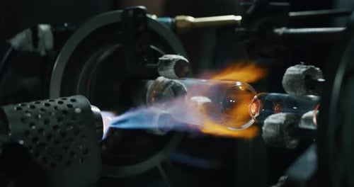 Slow motion of experienced glass blower working with flame on a handmade art piece of glass from p