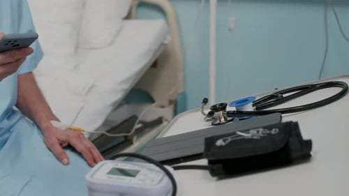 Aged Patient Browsing on Smartphone while Getting IV Treatment in Clinic