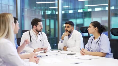 Group of doctors communicate at conference in clinic office boardroom. Team of workers physicians