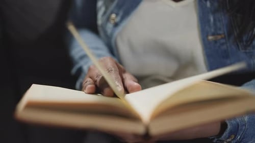 Woman Flips Pages of Textbook Looking for Information