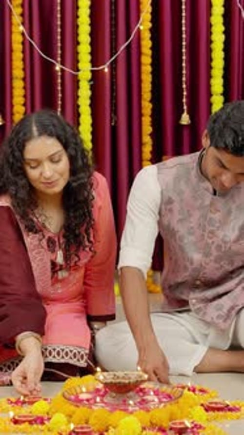 Vidéo verticale d'un couple indien plaçant des diyas autour de Rangoli