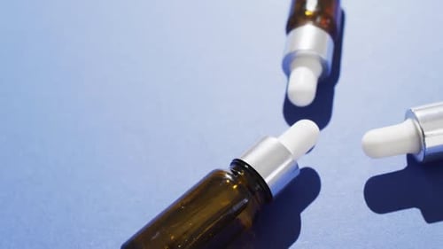 Close up of dropper serum bottles on blue background with copy space