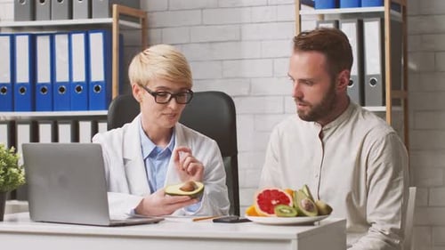 Un dietista consulta con un paciente varón sobre las opciones de alimentos saludables en la clínica