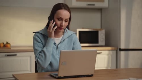 Woman Working on Laptop and Talking on Phone