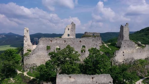 Aerial footage of a ruined medieval castle on a hill, Slovakia. Flying above revealing the forest.
