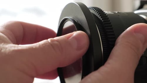 Close Up View of Camera Mechanic Installing Polarizing or Ultraviolet Filter on Lens of Professional