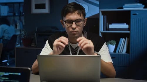 Young Man Typing on Laptop Computer in Office