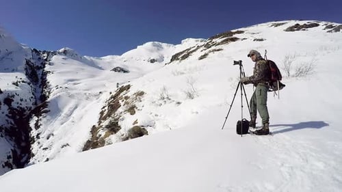 Photographer on Snowy Mountain Capturing Winter Landscape