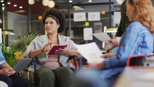 Happy disabled and diverse business people discussing work at office