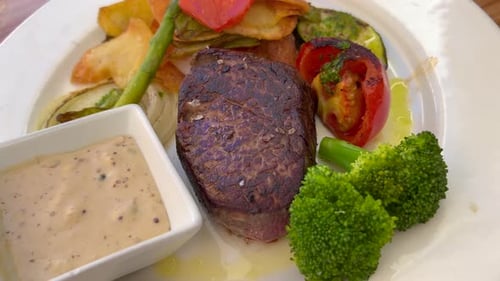 Juicy sirloin fillet steak with peppercorn sauce, vegetables and potatoes at a restaurant, delicious