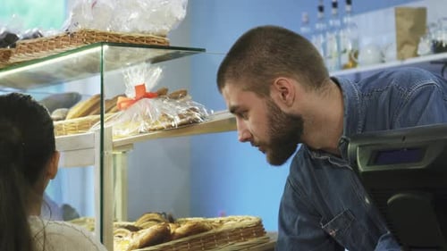 Charming Male Baker Engaging with a Delighted Little Girl at His Bakery