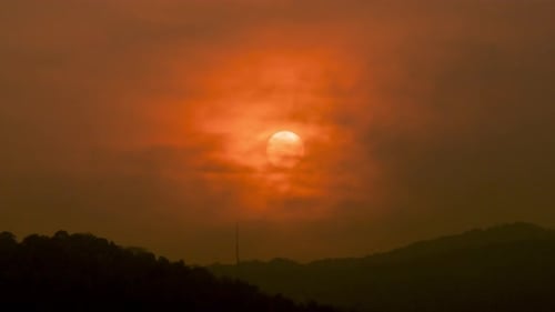 Zeitraffer des Sonnenuntergangs über wolkenbedeckten Hügeln.