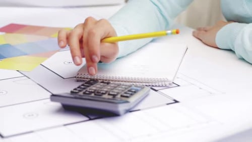 Architect Using Calculator and Pencil at Desk