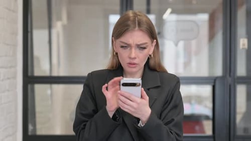 Worried Young Adult Using Phone in Workplace