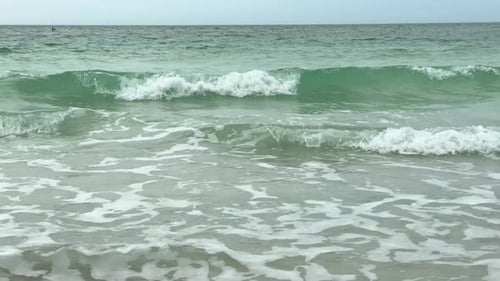 A relaxing day by the side of the ocean on the sandy beach as the waves come rolling in.