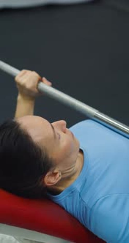 Middleaged Woman Focuses on Building Pectoral Strength with Bench Press in the Gym