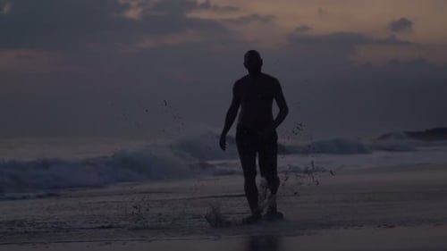 Silhouette of Man Walking Near Sea and Splashing Water in Evening Adult