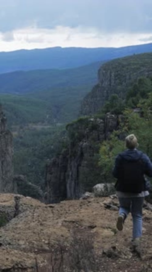 Millennial Woman Reaching Canyon Edge with Raised Arms