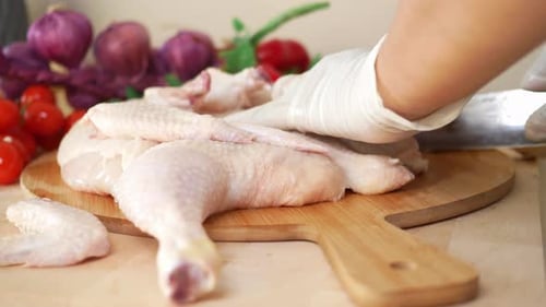 Cutting up Raw Chicken with Knife on Board
