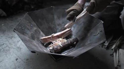 Hands preparing kindling for starting a small fire