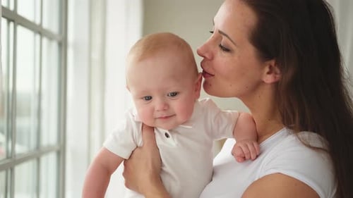 Mother Holds Baby in Brightly Lit Interior