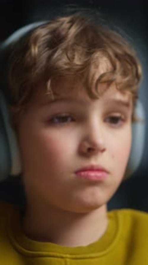 Closeup of a Thoughtful Young Child Wearing a Mustard Yellow Sweater and White Headphones Focusing