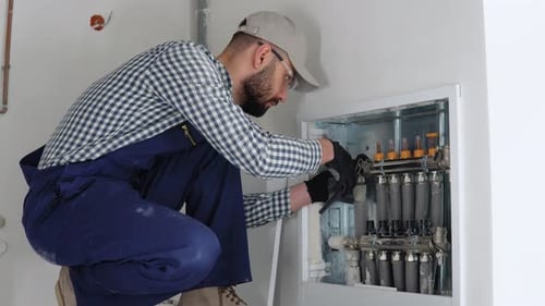 Man Adjusting Pipes with Tools Indoors