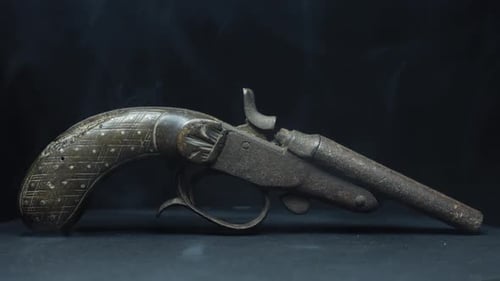 Antique Rusty Flintlock Pistol Enveloped in Wisps of White Smoke