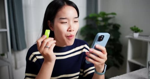 Woman Eating Apple While Using Smartphone Indoors